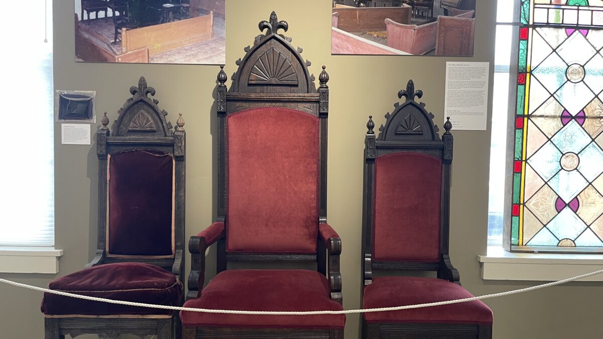 A collection of red chairs occupies the room, illuminated by a stained glass window.