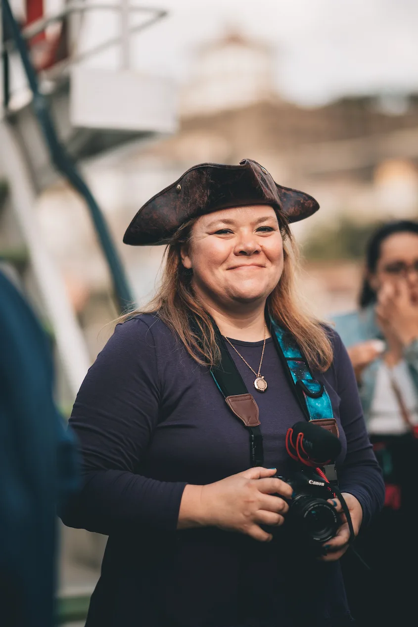 Courtney Robertson wearing a pirate hat, a DSLR camera, and a purple shirt