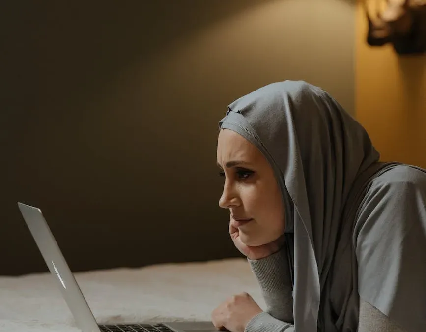 woman in gray hijab using macbook air