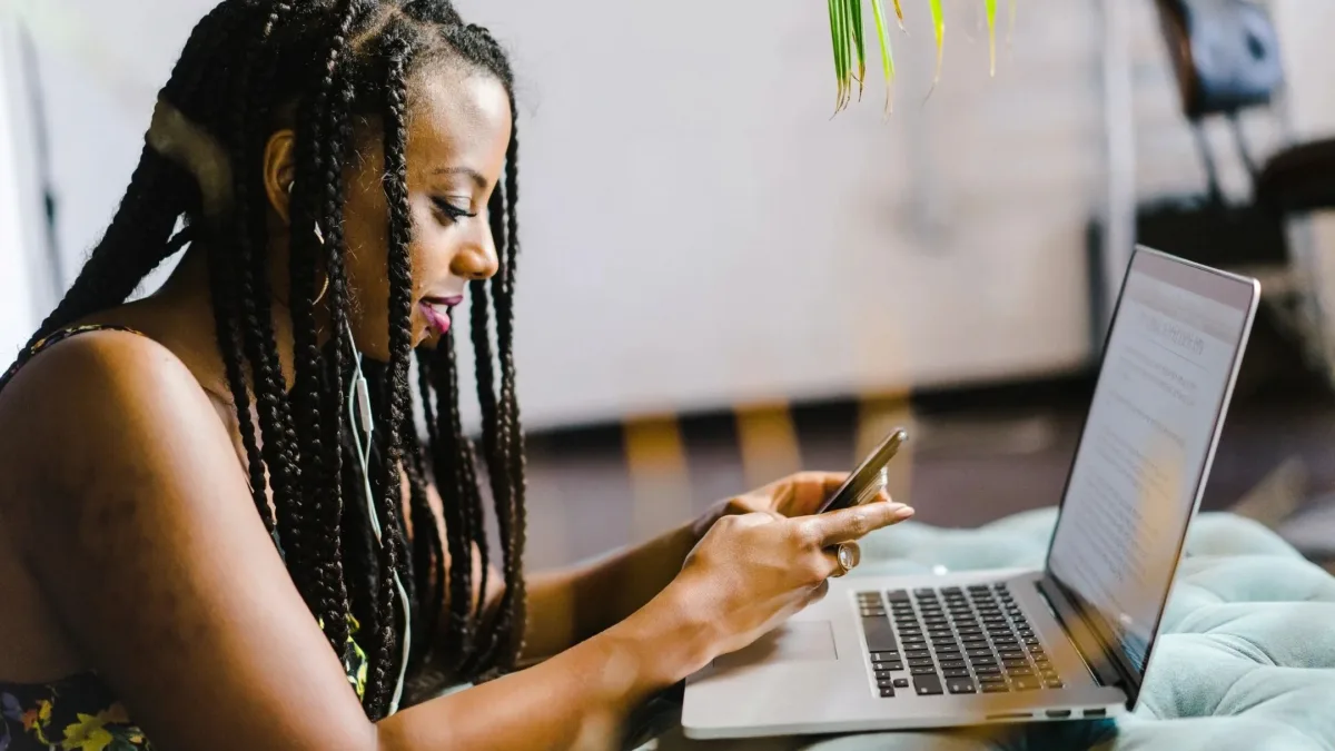 Woman looking at mobile phone and laptop screen