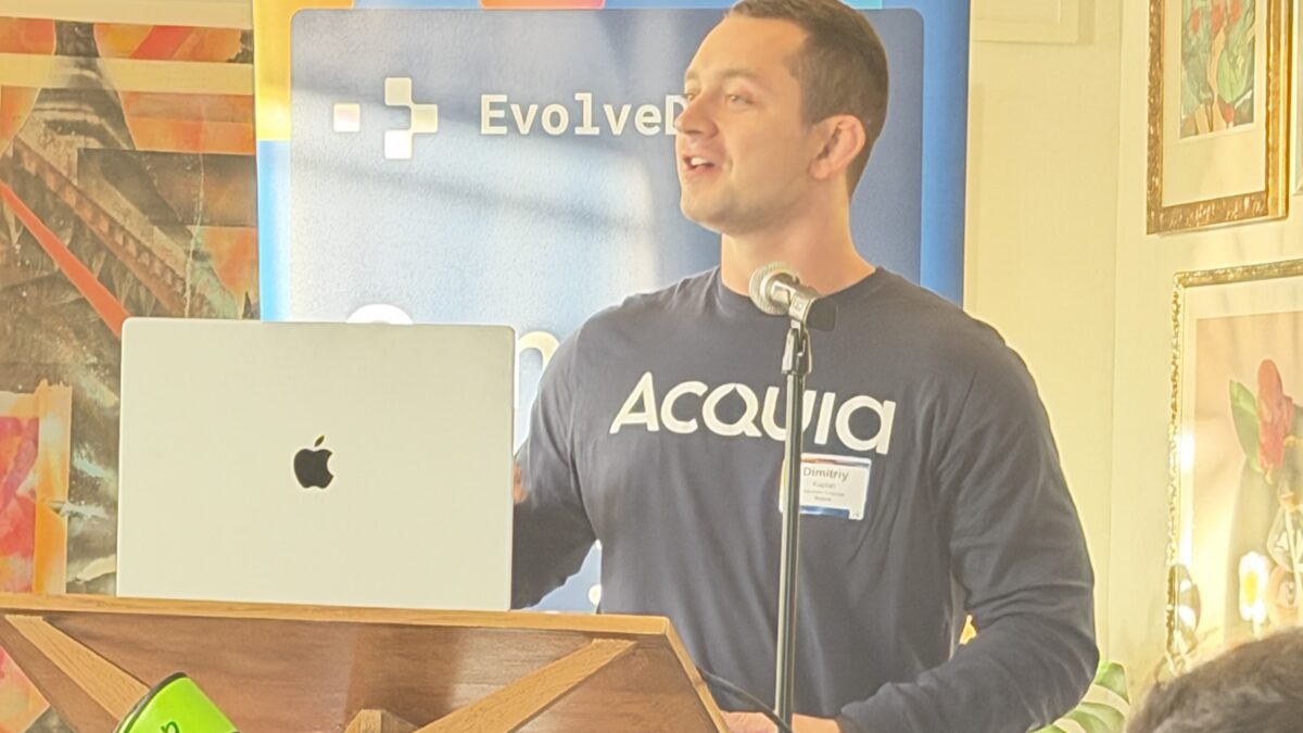 Dimitriy Kaplan of Acquia presents at a podium beside an EvolveDigital banner draped with neon green boxing gloves
