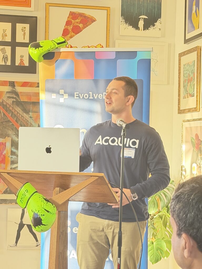 Dimitriy Kaplan of Acquia presents at a podium beside an EvolveDigital banner draped with neon green boxing gloves