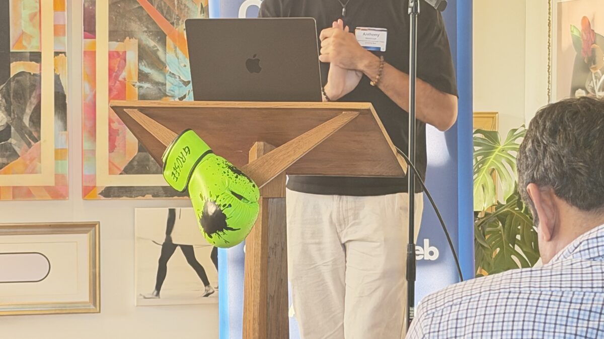 Anthony Bradshaw of Evolving Web speaks at a podium beside an EvolveDigital banner draped with neon green boxing gloves